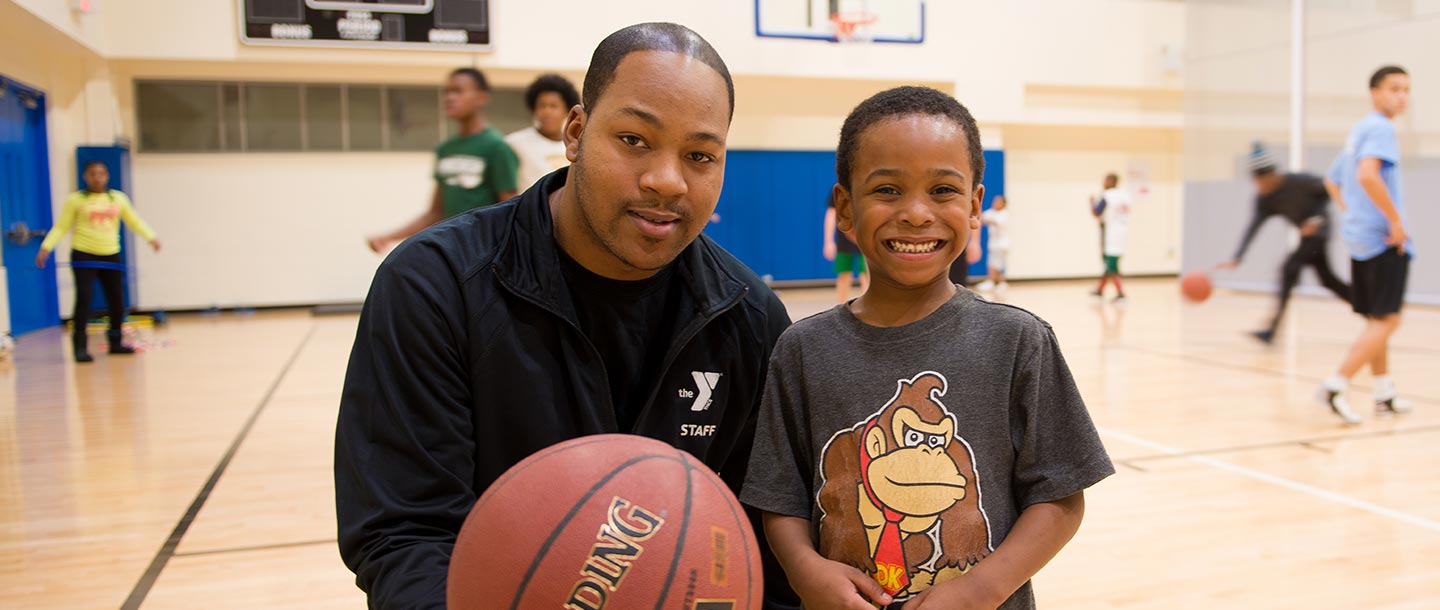 Young boy with basketball instructor at YMCA
