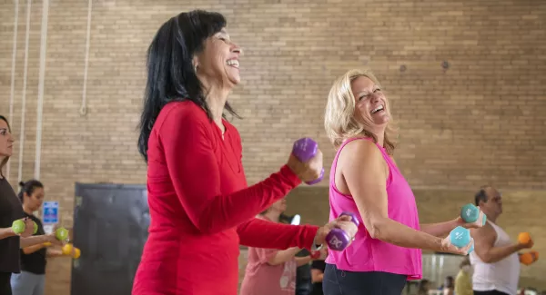 2 women lift weights in class