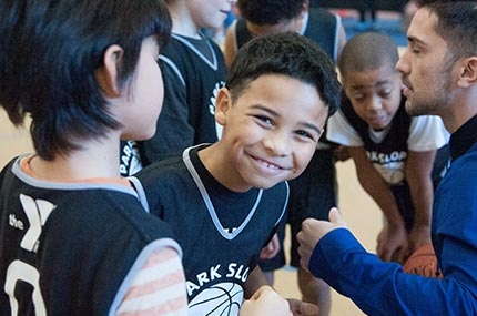 Boy in basketball team huddle at Park Slope Armory YMCA in Brooklyn smiles
