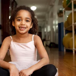 Girl sitting on floor of Park Slope Armory YMCA hallway in ballerina tutu