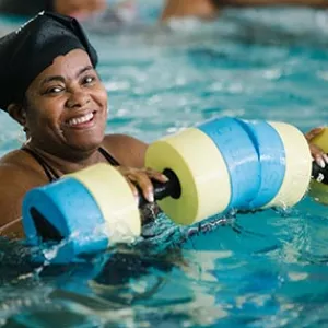 Woman smiling in Bronx YMCA indoor pool during water aerobics class