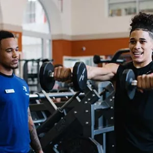Man lifts weights with personal trainer