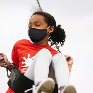 A girl in a mask on a swing at Y camp