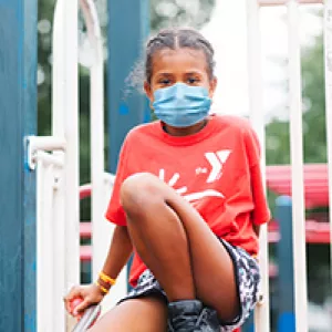A girl in a mask playing outside at Y camp