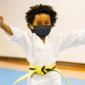 A boy in a mask in karate class at the YMCA