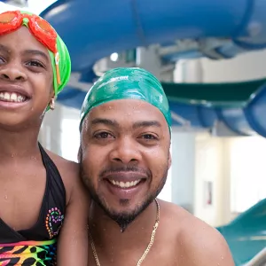 A father and a daughter posing for a photo in the pool