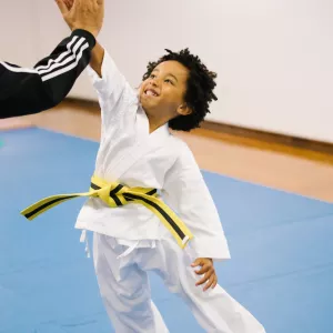 kid in karate uniform high fives