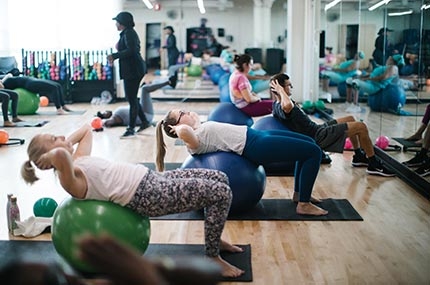 Workout class on yoga mats using balls to do core training exercises at Rockaway YMCA fitness studio