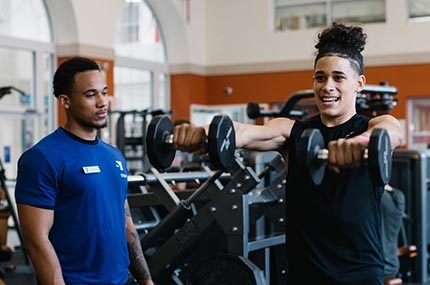 Man lifts weights with personal trainer