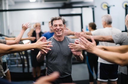 Man high fives classmates in YMCA fitness class
