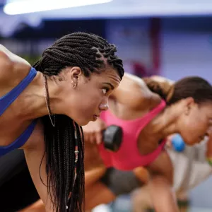 Women lift weights in a group fitness class.