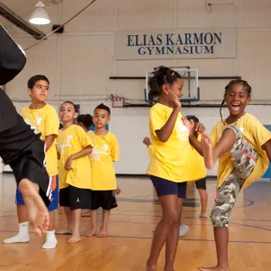 Kids doing martial arts in the gym, led by an instructor, at the Bronx YMCA Summer Day Camp.