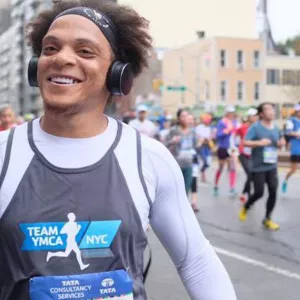 A marathon runner wearing a YMCA bib high fives a passerby.