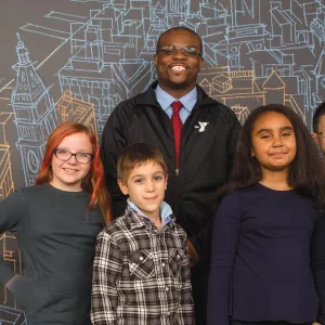 A group of kids and a Y staff member standing in front of a map of NYC.