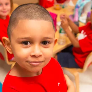 A toddler stands in front of a group of campers at the Ridgewood YMCA summer day camp.