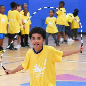 Boy jumping room in Jamaica YMCA indoor basketball court during summer camp