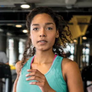 Woman in green tank top running on treadmill at gym