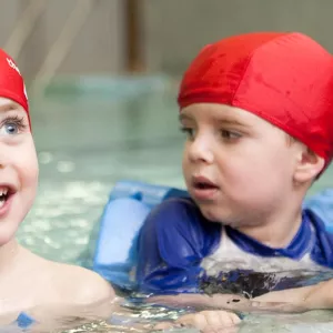 Preschoolers holding onto side of pool for swim class