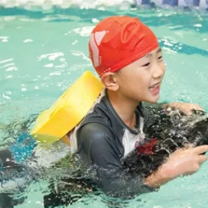 Boy with backpack and kickboard learns to swim at Vanderbilt YMCA summer camp