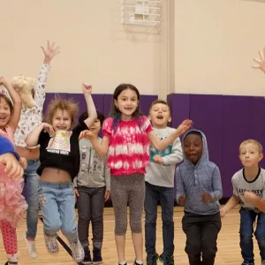 Class of preschool kids jumping in YMCA gym