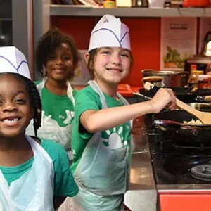 Three YMCA summer campers cooking over stove