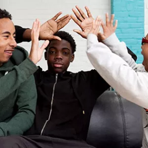 Three teenagers high five each other at the YMCA.