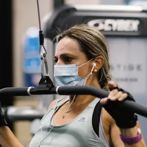 A woman in a mask works out on strength training equipment at the YMCA.